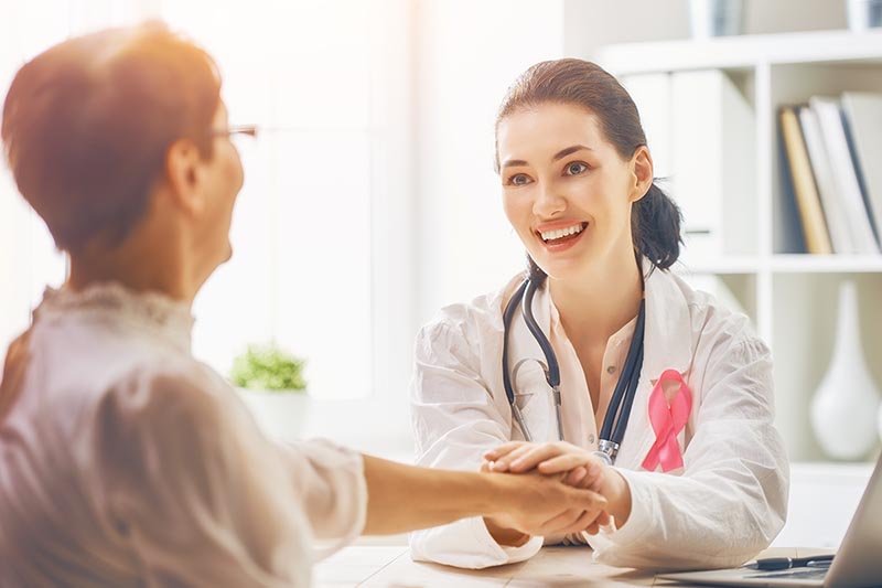 Female doctor listens to female patient about breast cancer diagnosis. 