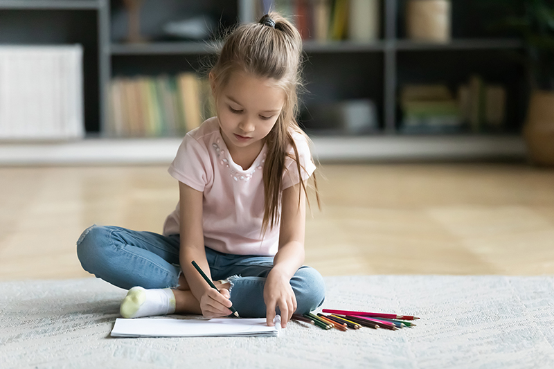 Little girl coloring sitting on the floor, how to keep kids entertained while stuck indoors