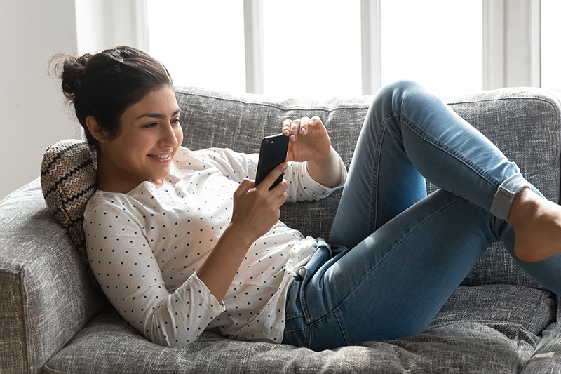 Woman on the couch on her phone, showing us how she is connecting with people during social distancing