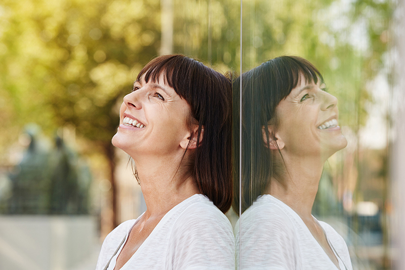 Happy woman in front of a mirror, how to practice self love