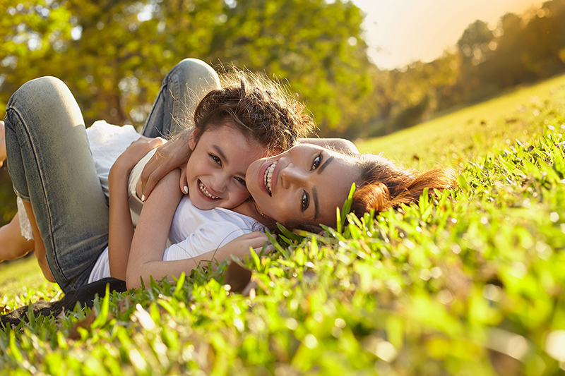 Mom and daughter outside on the grass smiling, how to cultivate happiness and gratitude