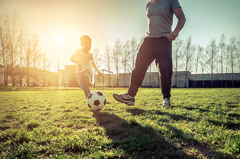 Father and son playing soccer, finding ways to optimize their health