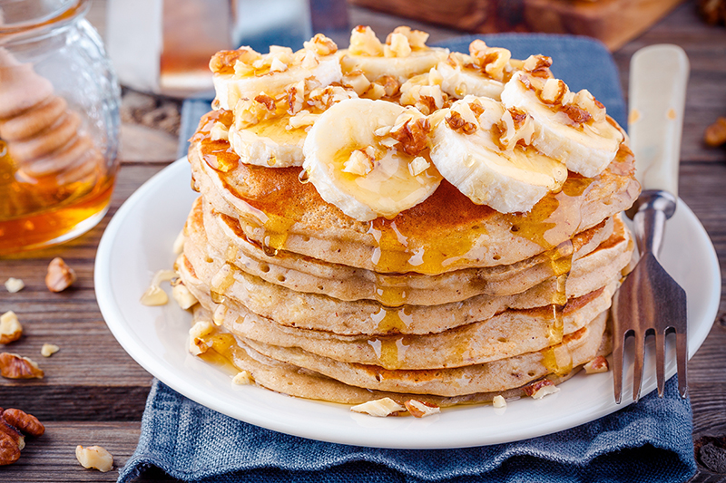 Banana oatmeal blender pancakes on a plate with bananas and nuts, recipe