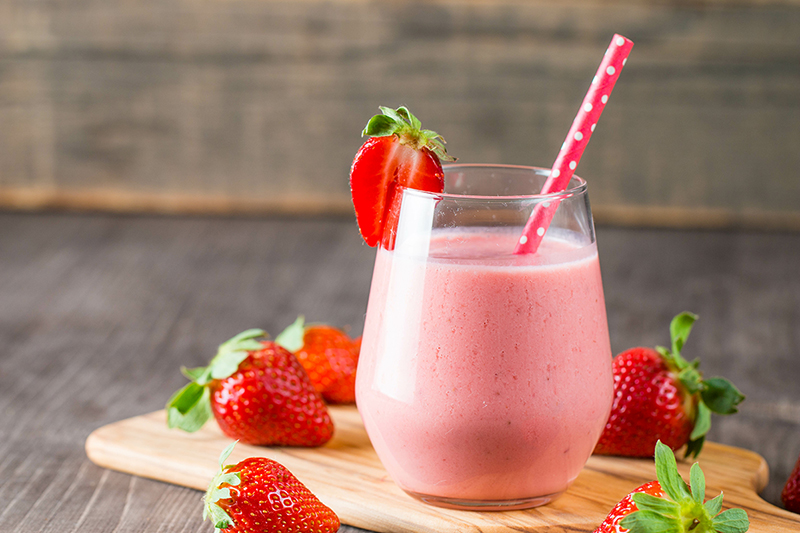 Strawberry and yogurt smoothie on a cutting board with straw, recipe