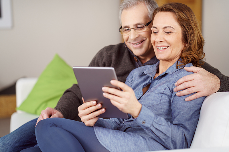 Man and woman on couch shopping for Medicare plans, important dates to remember lg