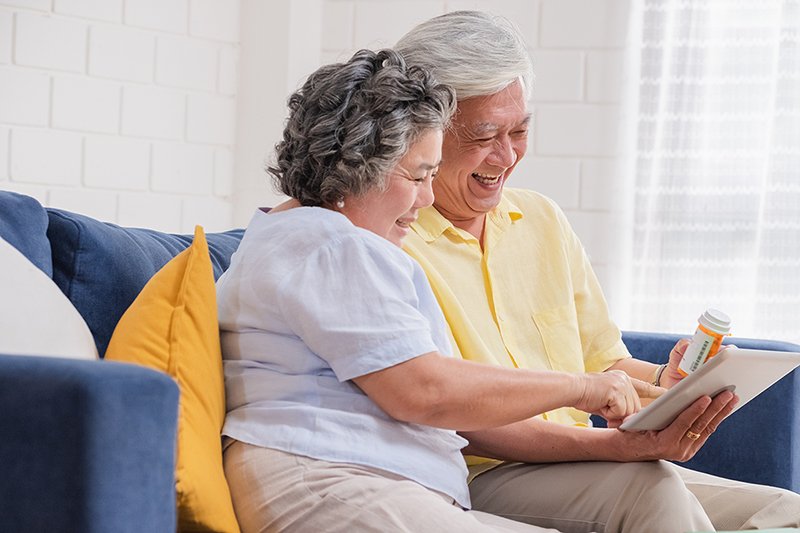 Couple on couch review Medicare Advantage plan and prescription. 
