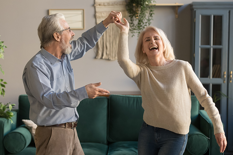 Older couple smiles and dances in their living room. 5 healthy habits for seniors, stay in shape, lg