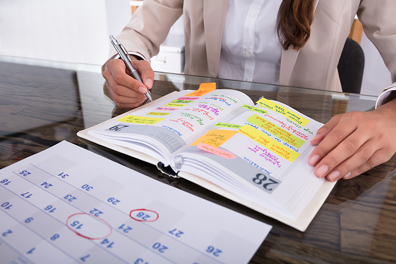 Woman sits at her table and works out her schedule, 7 time management tips