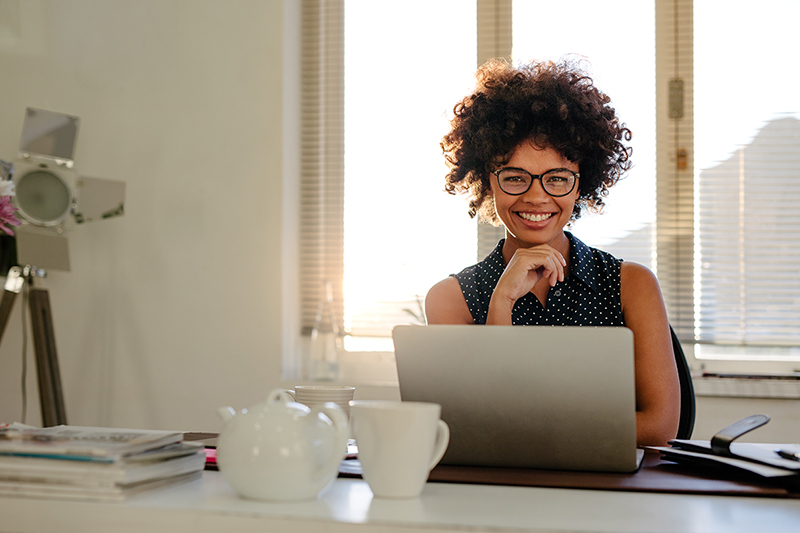 Woman sitting at her desk in her office, what are the benefits of organizing your office?