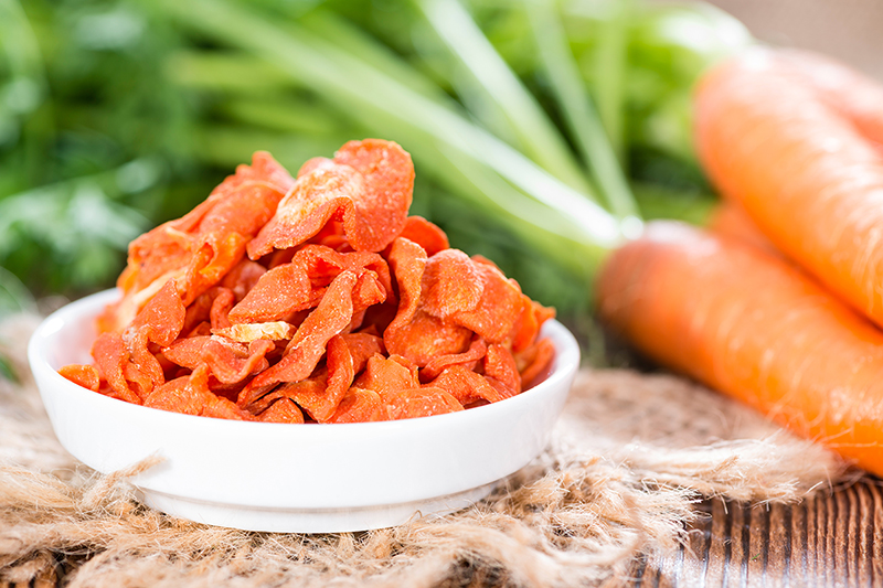 A bowl of healthy freshly baked carrot chips on a table.