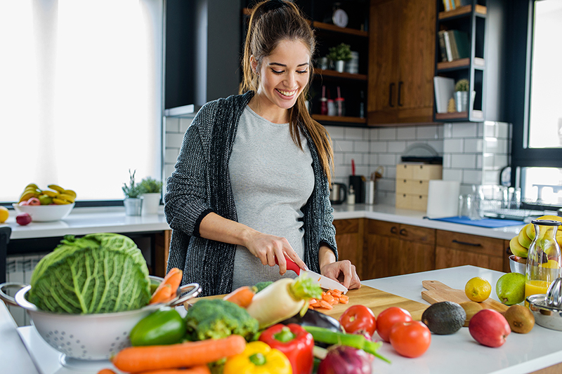 Woman cutting weight loss friendly foods and vegetables in the kitchen.