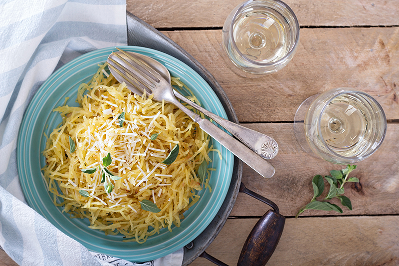 A bowl of herbed spaghetti squash that is topped with Parmesan cheese and garlic.