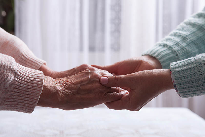 Caregiver holding hands with a loved one with a chronic illness