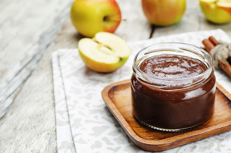 A jar of slow cooker apple butter sits on the table.