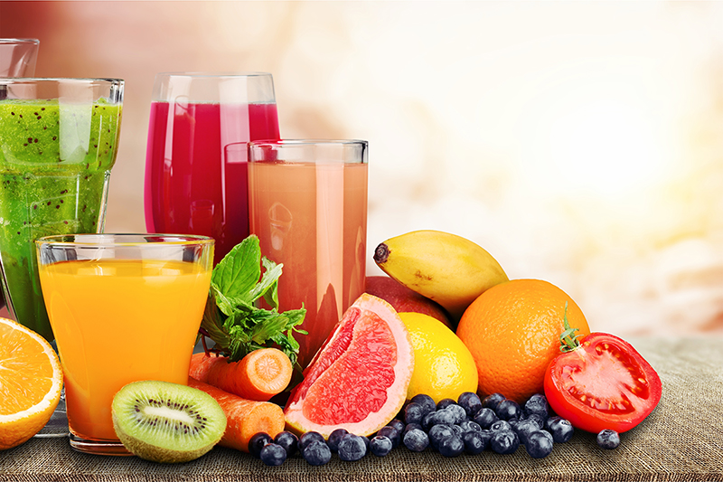 Fruits and glasses of fruit juice on a table.