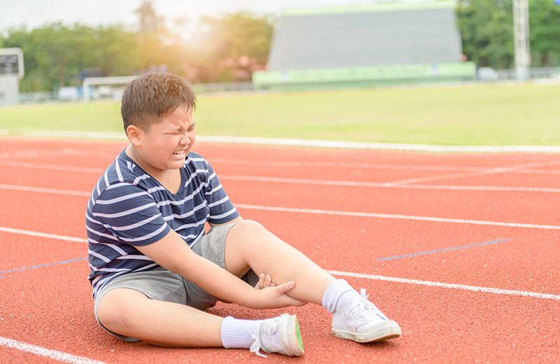 Young Hispanic boy feeling muscle pain caused by growing pains.