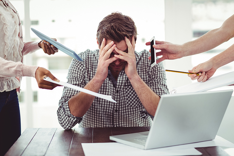 Young businessman is stressed at work from multitasking.