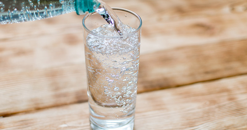 Sparkling water or mineral water is poured into a clean glass.