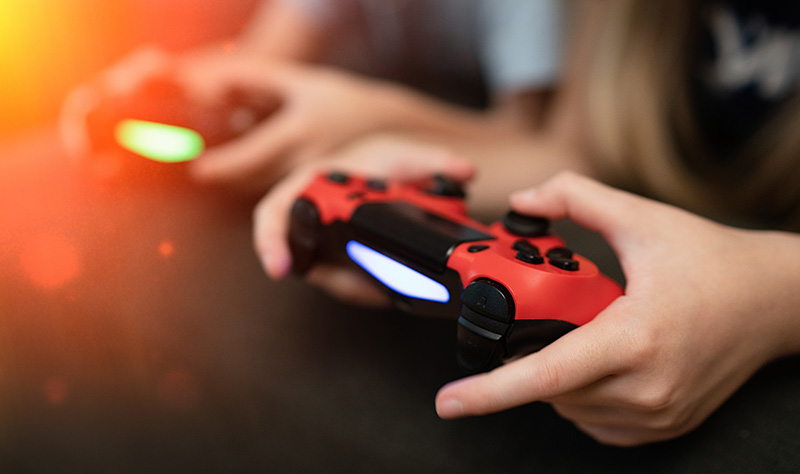 Child spending too much time playing video games with red controller. 
