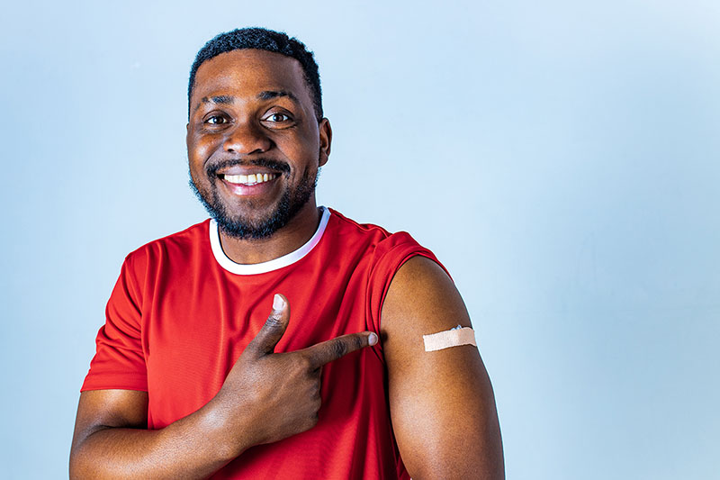 Man smiles and points to his arm where he got his COVID-19 vaccination.