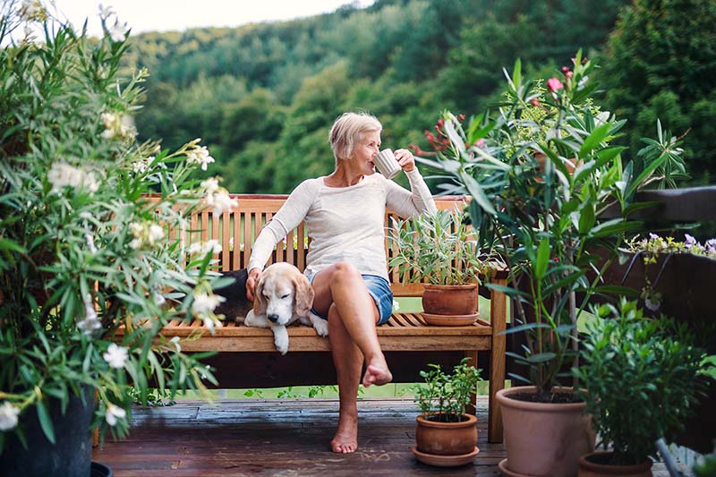 Happy senior woman with dog sits outside with a dog and enjoys retirement.