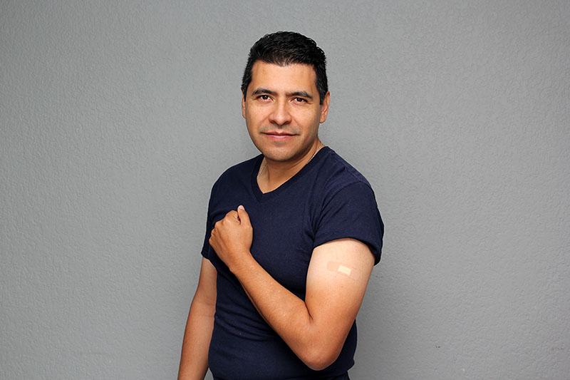 Latino man shows off arm where he got his COVID-19 vaccination.