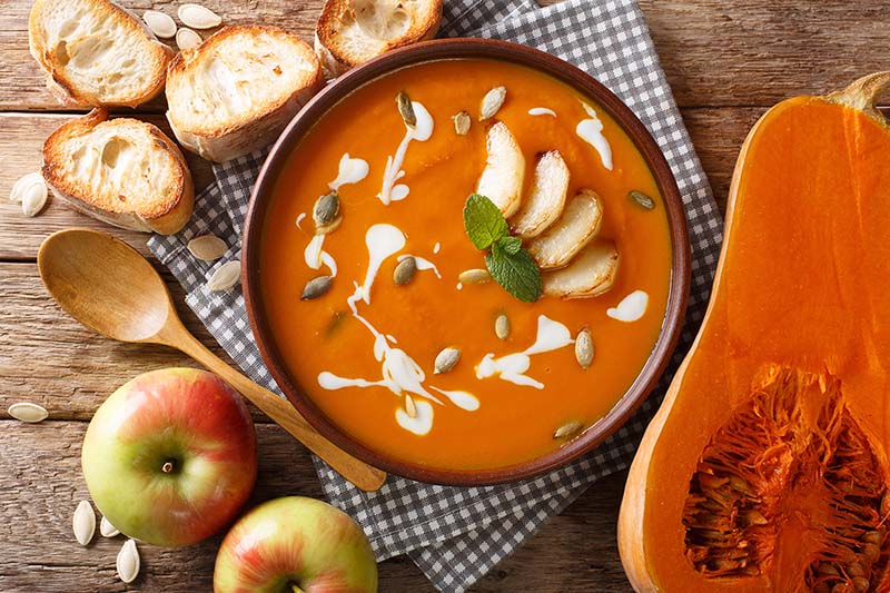 A hot bowl of butternut squash soup lays on the table.