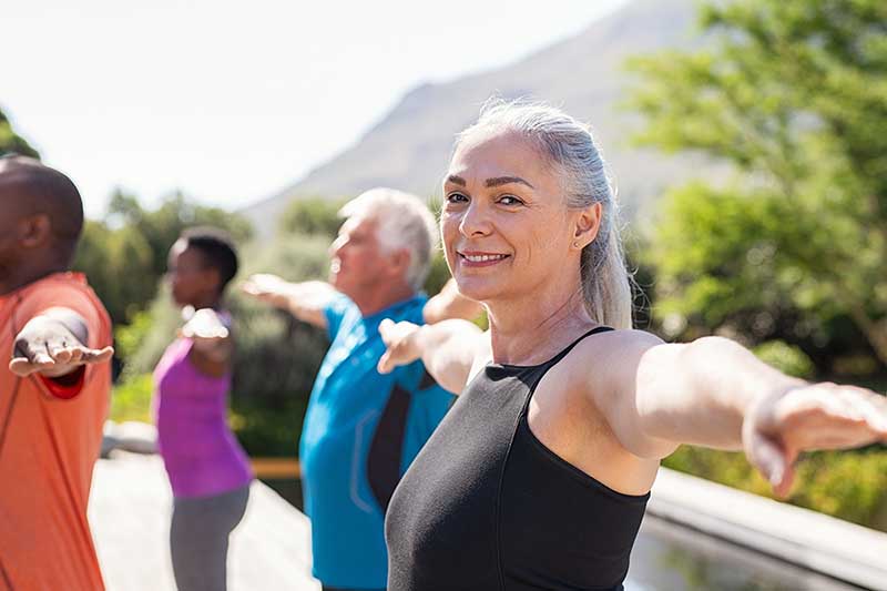 Senior woman balances outside during exercise program. 