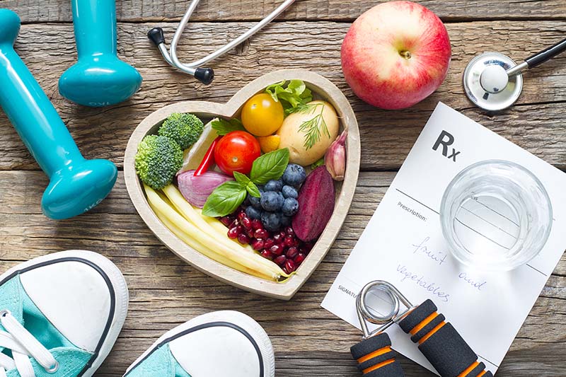 Heart healthy foods in heart-shaped bowl is surrounded by other heart healthy items.