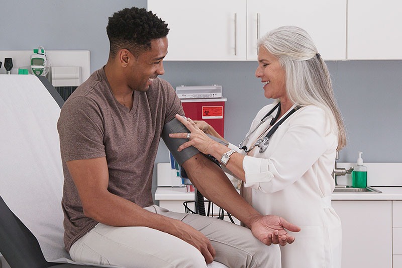 Young male patient in medical room having blood pressure checked by doctor.