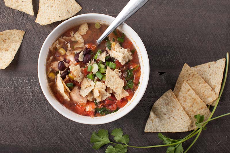 A bowl of warm and healthy taco soup on the table with chips.