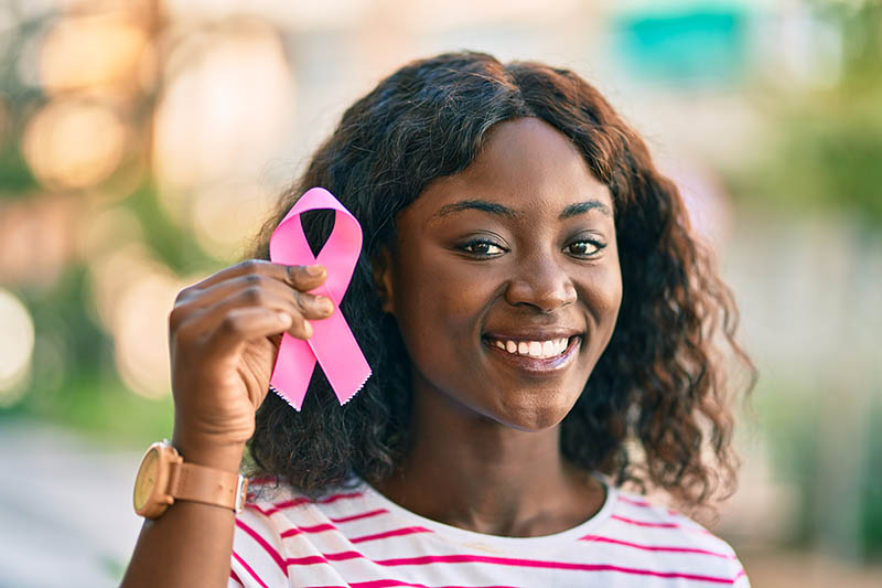 Young girl holds up breast cancer awareness pink ribbon.