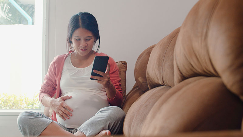 Embarazada feliz mira a su plan de salud en la aplicación móvil de Select Health.