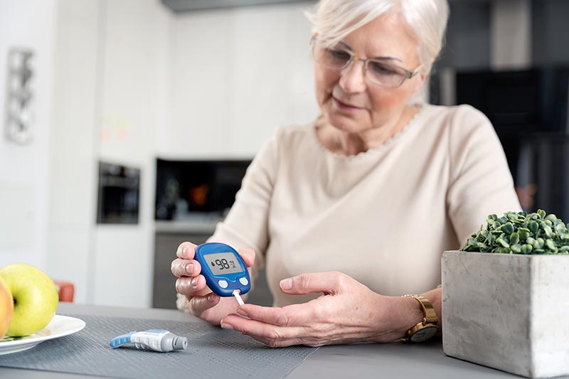 Older woman with diabetes tests blood sugar levels.