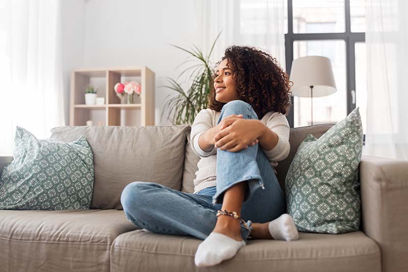 Young woman with Type 1 Diabetes sits on sofa at home.