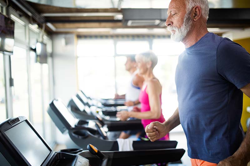 Older male receives Select Health discount to join health club and run on treadmill. 