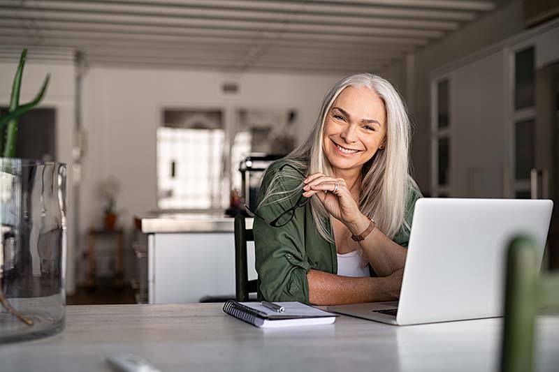 Una mujer feliz sonríe mientras trabaja en una computadora revisando herramientas para miembros.