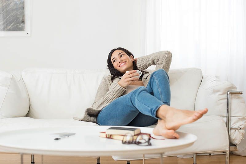 Woman smiles while sitting on the couch to rest and recharge.