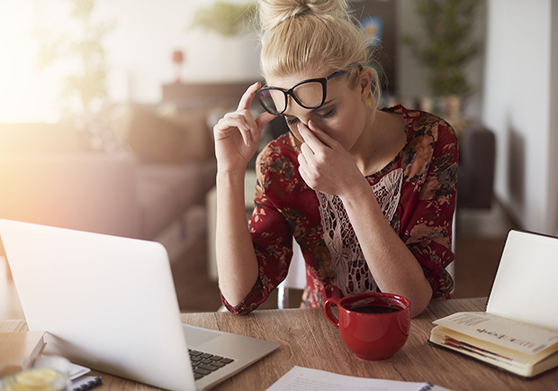 Woman with a headache looking at her computer. Types of headaches.