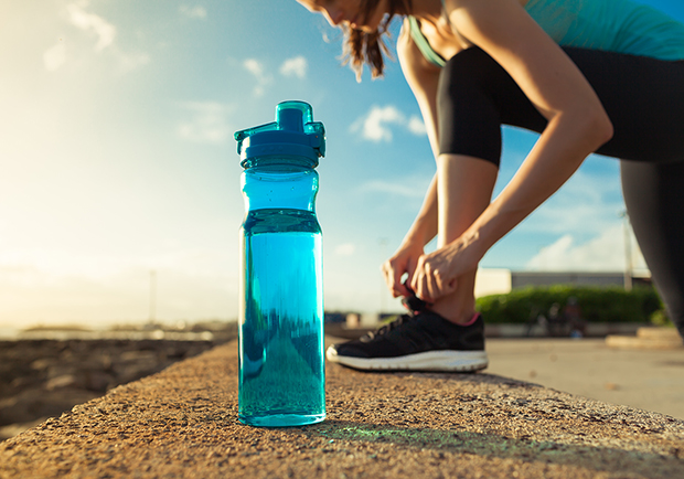 Girl working out, stretching next to a water bottle. 