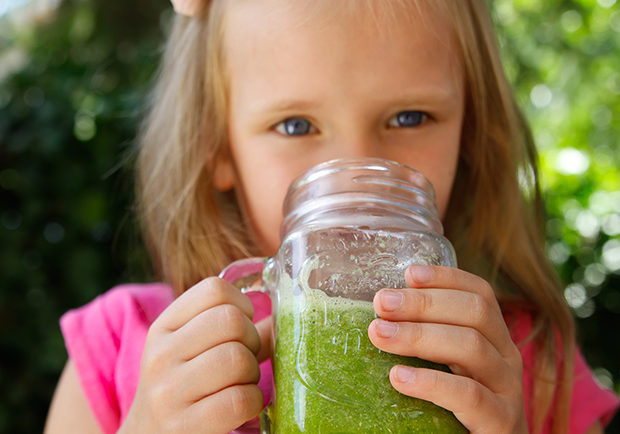 Young girl drinking a healthy green smoothie, healthy drinks for children