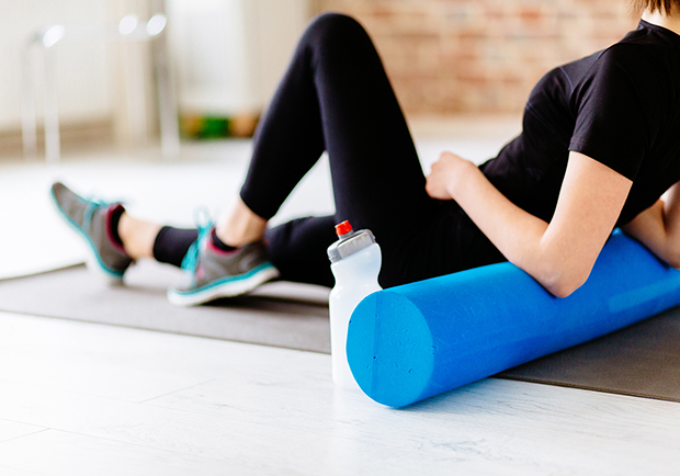 Woman using a foam roller after a workout, learn what the benefits to foam rolling are