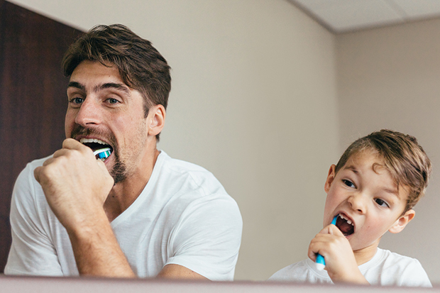 Father and son brushing their teeth, dental health