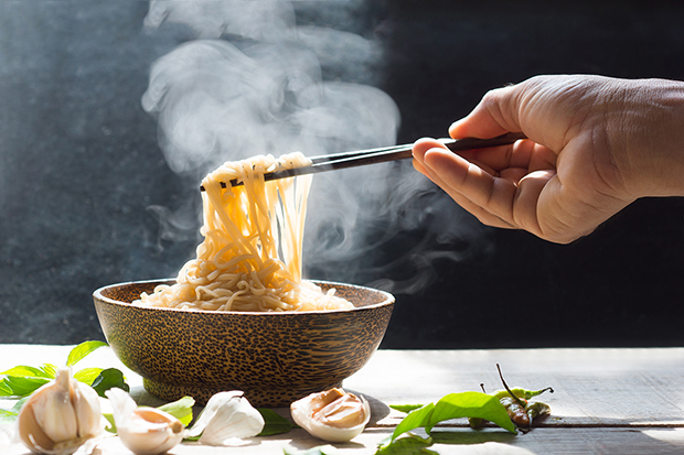 Hand eating noodles with chopsticks, healthy eating around the world