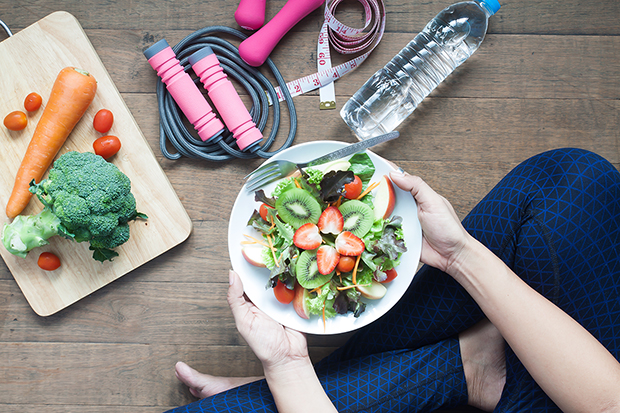 woman holding a healthy plate of food and exercising, ways to help prevent cancer