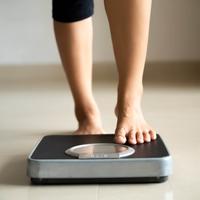 Person weighing themselves on scale 