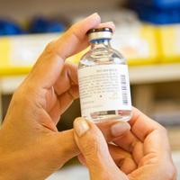  a pharmacist holds up a vial of medication