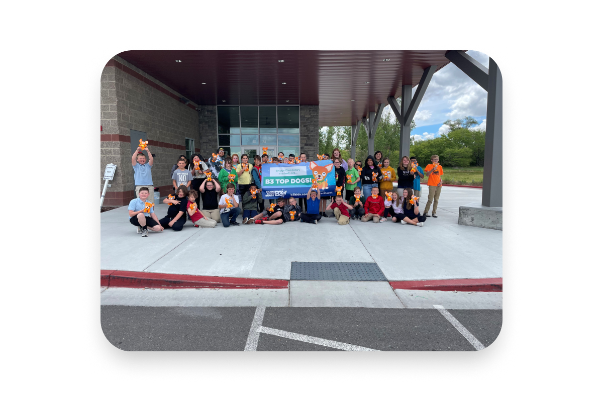  students with teachers in front of school holding B3 Top Dogs Banner and stuffed dogs wearing sunglasses