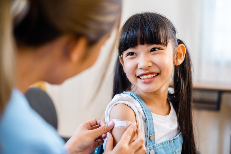 Child smiling after receiving bandaid from nurse.