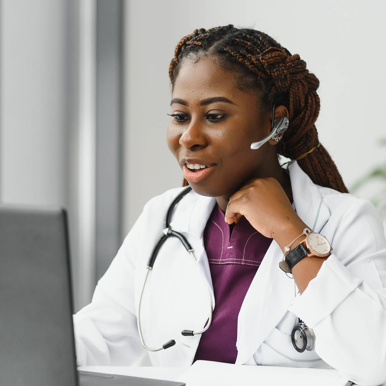 A woman doctor with a stethoscope and headset with microphone, laptop